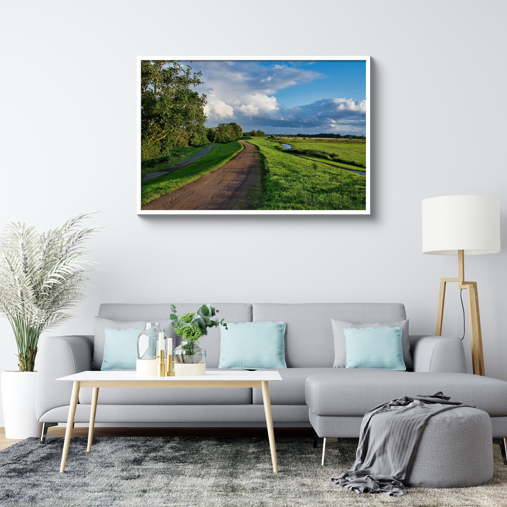 Photo de paysage sur plexiglas dans un cadre blanc, au-dessus d’un canapé gris dans un salon lumineux