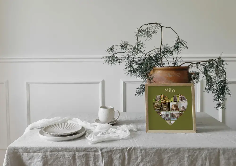 Collage photo de chats en cœur sur fond olive avec prénom, dans un cadre en bois posé sur une table dressée