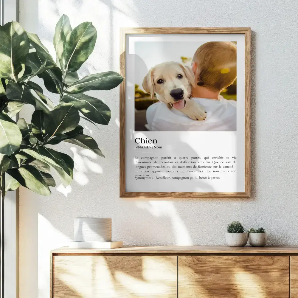 Affiche définition du chien avec photo de chiot, dans un cadre en bois au-dessus d’un buffet près d’une plante