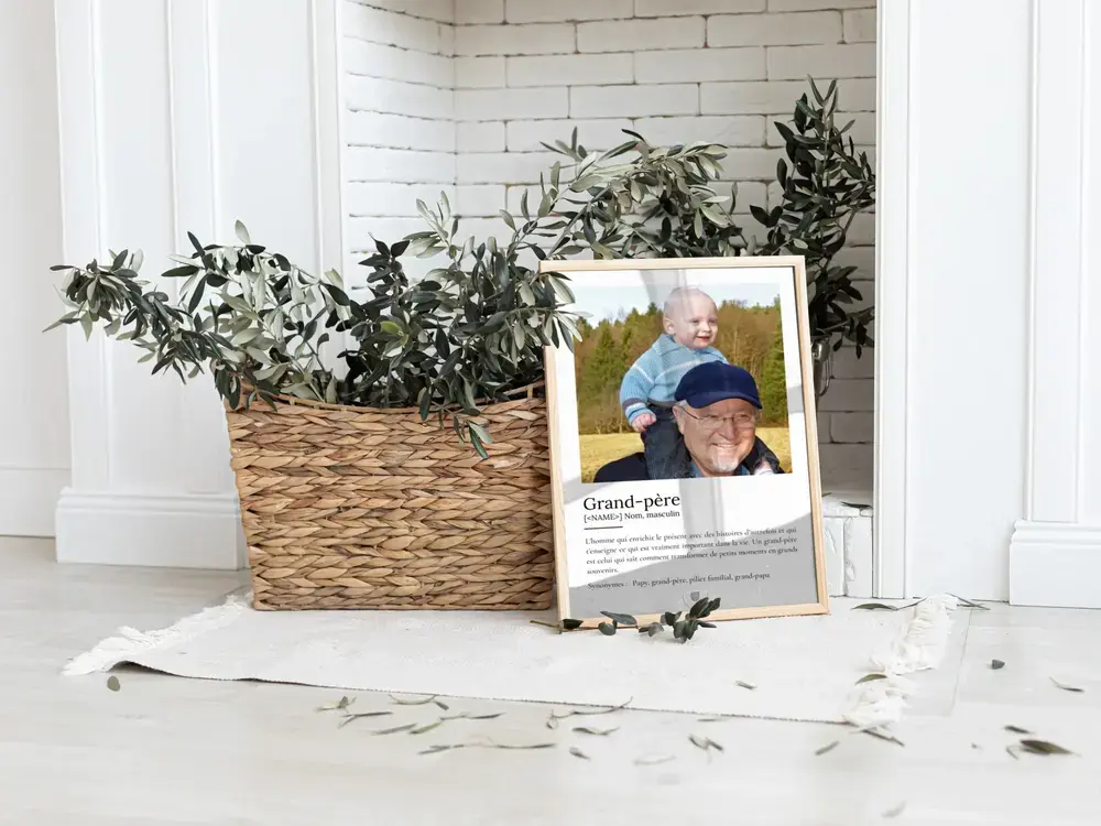 Affiche définition de grand-père avec photo de famille, encadrée et posée au sol près d'un panier tressé