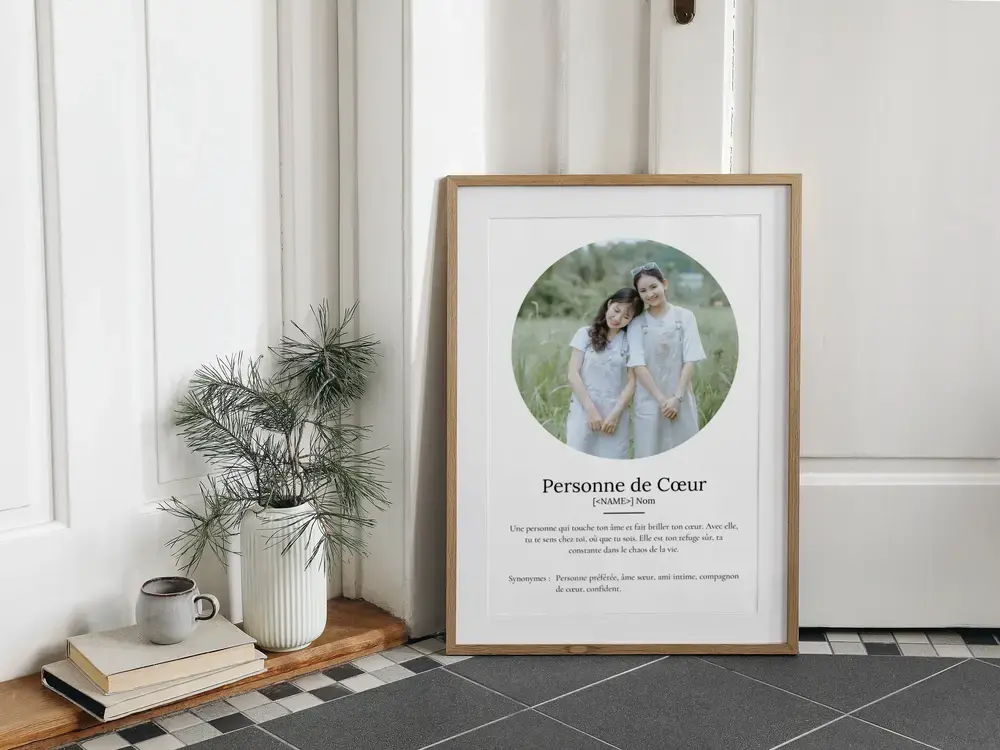 Affiche avec photo ronde et définition de l’amitié, encadrée en bois clair et posée au sol près d’une plante