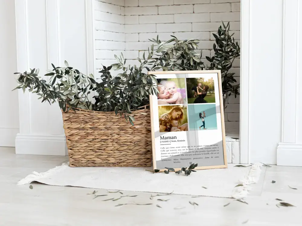 Affiche définition de maman avec quatre photos, cadre en bois posé au sol près d’un panier de feuillage