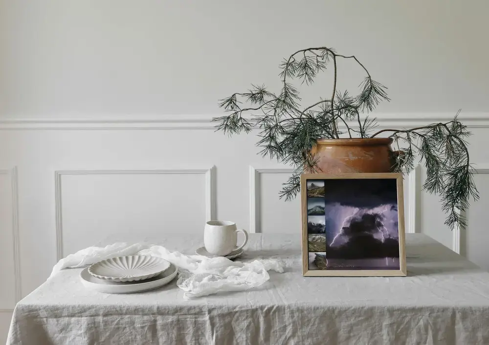 Pêle-mêle photo encadré avec éclairs et montagnes brumeuses, sur une table nappée à côté d'une tasse