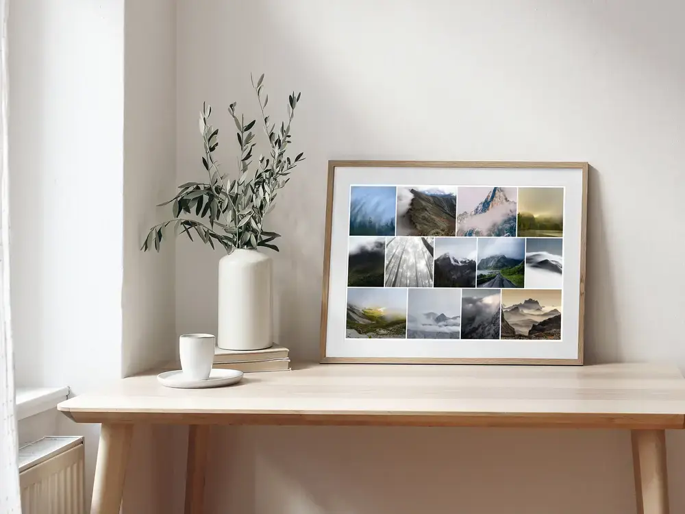 Pêle-mêle photo de montagnes brumeuses et de forêt, encadré en bois naturel sur un bureau près d'un vase